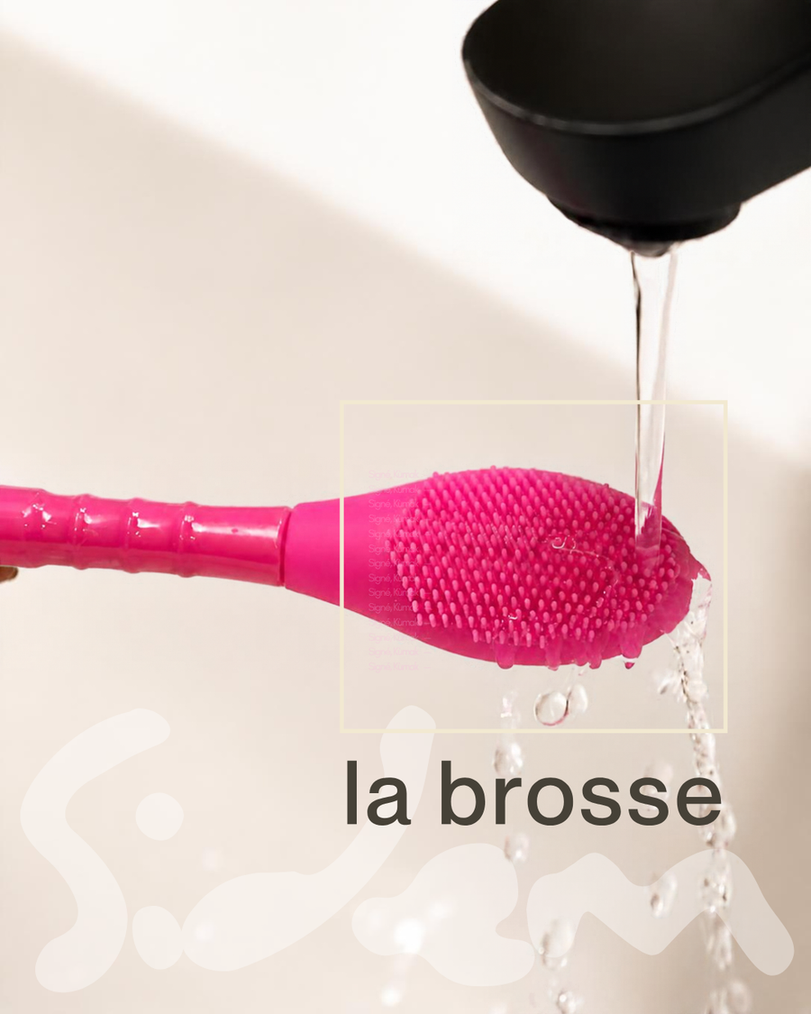 Brosse visage en silicone rose rincée sous l'eau du robinet